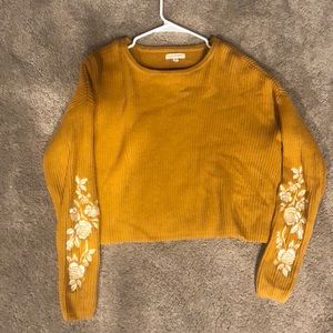 A yellow sweater with white embroidered flowers